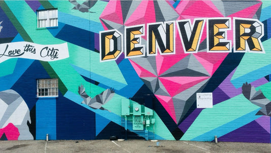 A colorful geometric street mural spelling "Denver" with the phrase "Love this City."