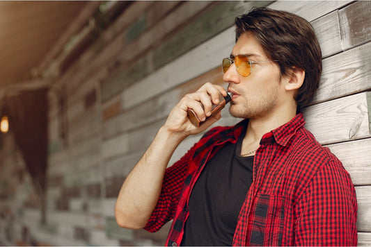 An adult male using a vape device outdoors