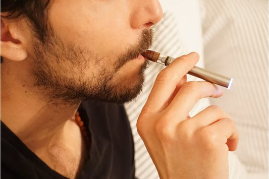 Close-up of a man in a black shirt using a vaping device