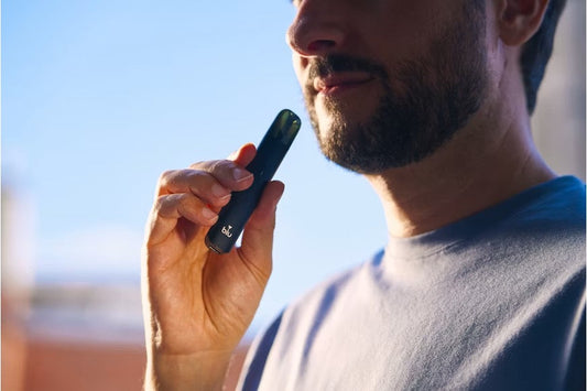 Person in a blue top holding a vape device