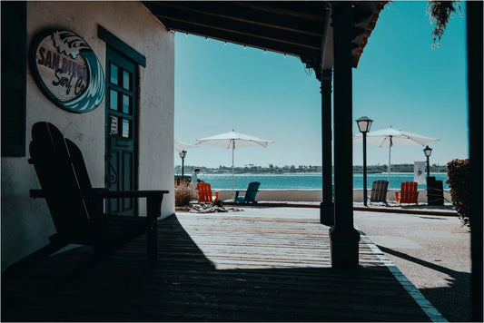 The covered porch of San Diego, looking out toward a beach lined with umbrellas and lounge chairs